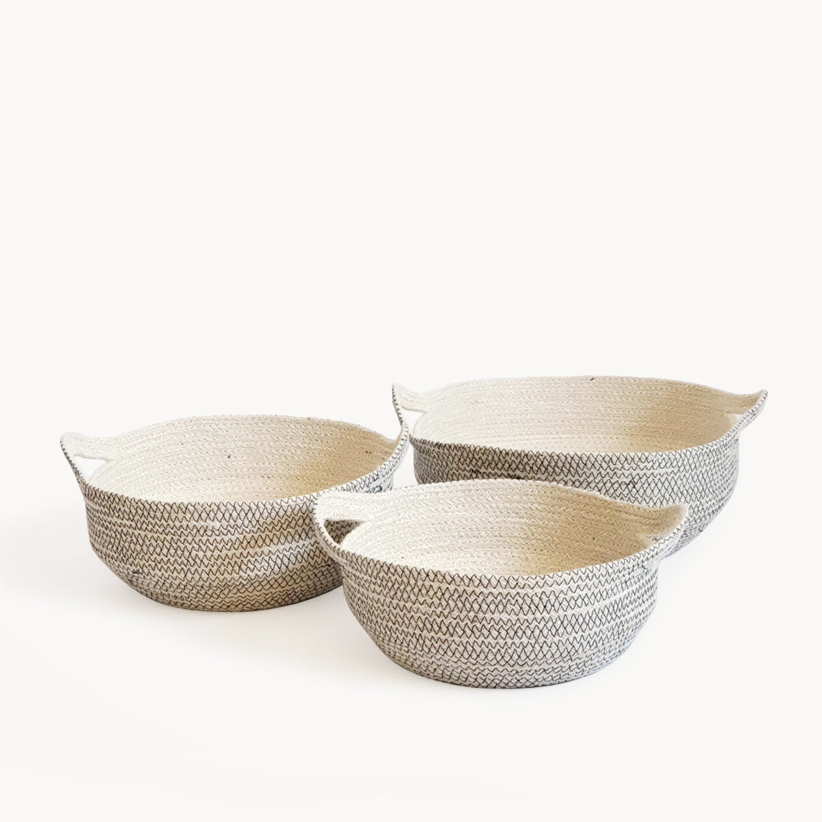 Three off-white and black handwoven jute baskets of different sizes arranged on a white background.