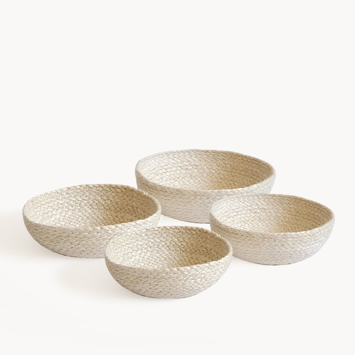 A set of four white handcrafted jute candy bowls on a white background.