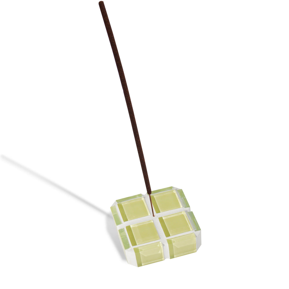 A yellow glass-tiled cube incense holder holding a single incense stick.