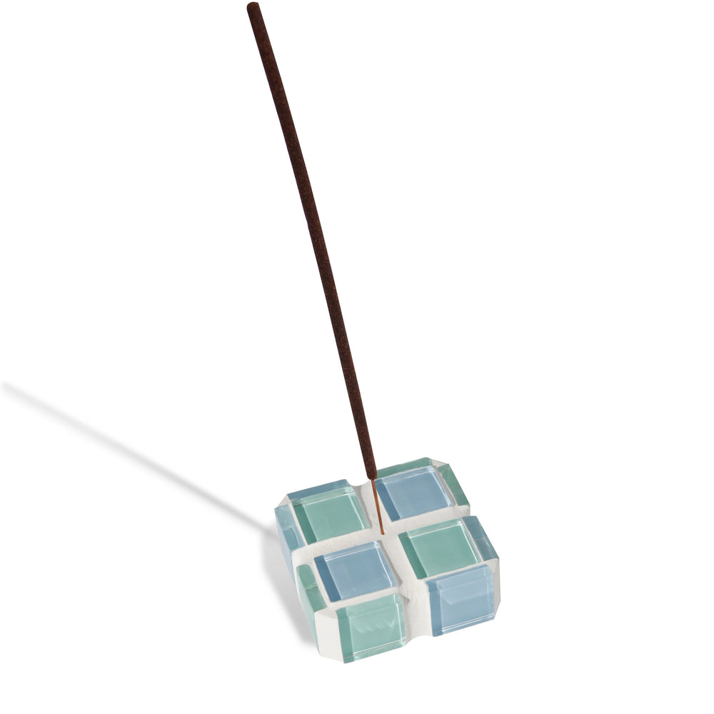 A blue and teal glass-tiled incense holder holding a single incense stick.