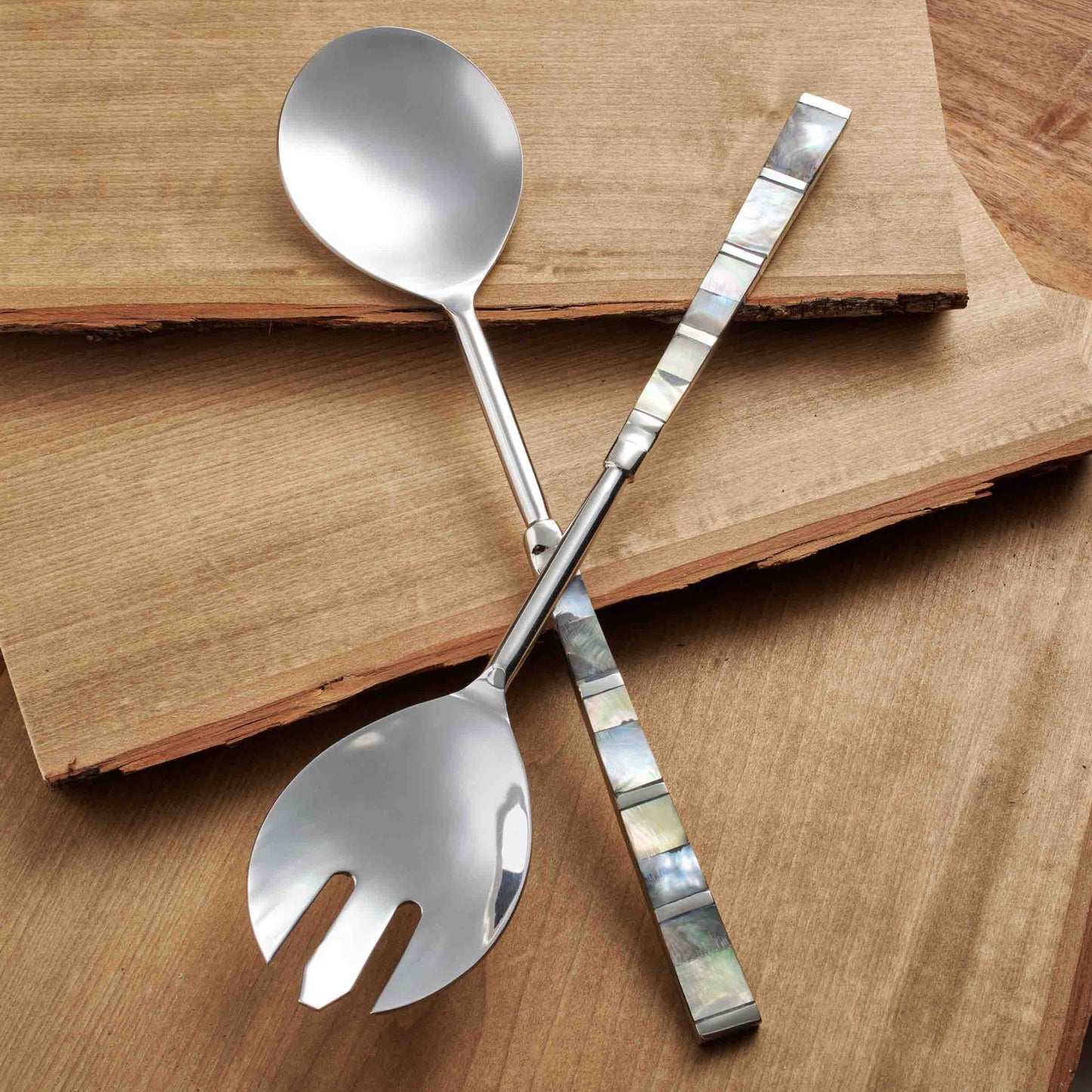 Mother of Pearl stainless steel salad servers set on a wooden surface