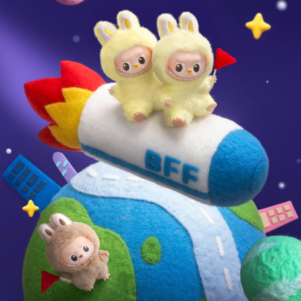 Toy rocket with two mini Labubu dolls on top and a smaller mini Labubu below, set against a colorful background.