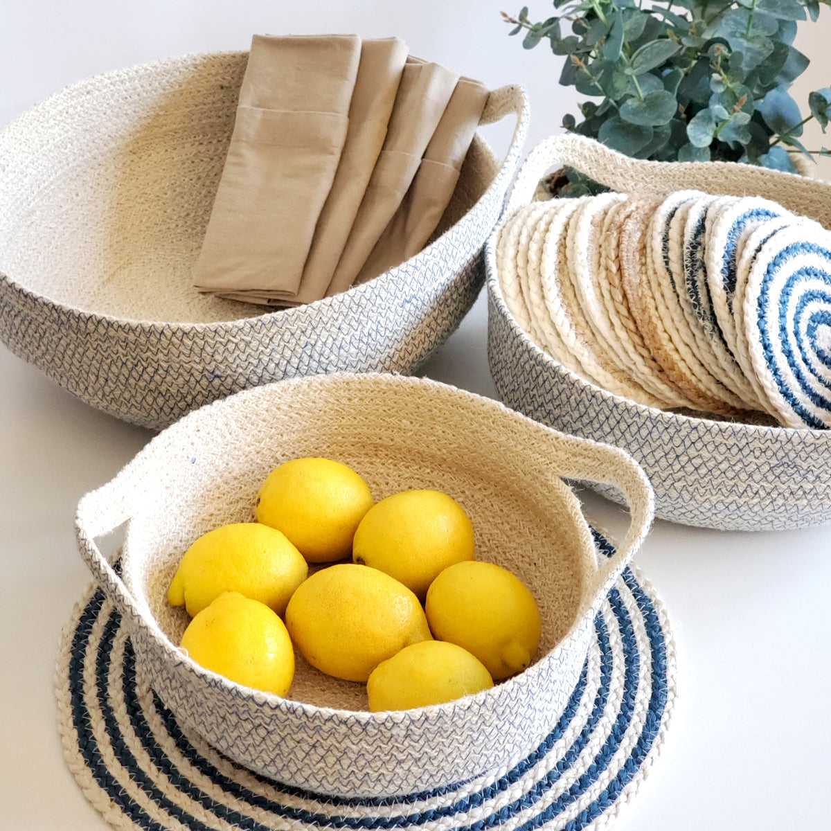 Woven baskets with lemons, napkins, and coasters on a light surface.