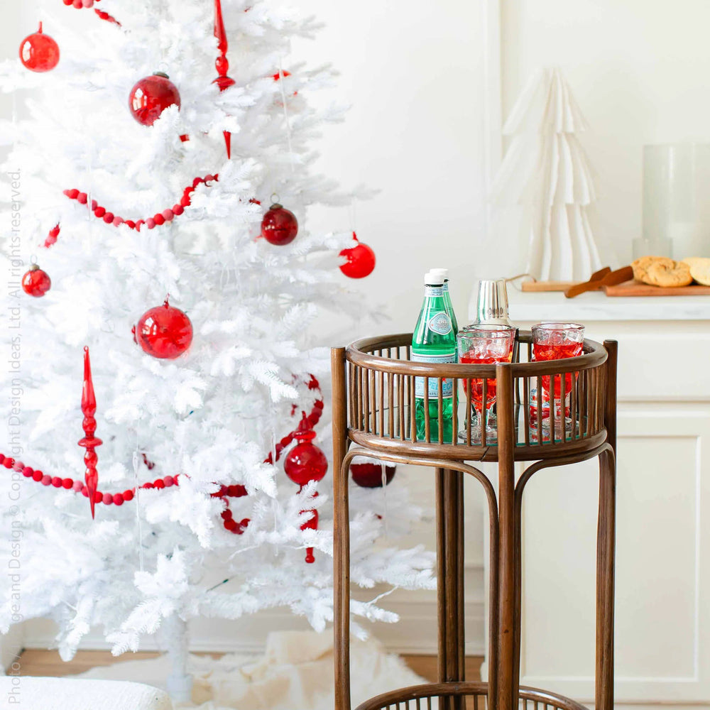 
                      
                        Moroah™ Mouth Blown Red Glass Ornaments on a white Christmas tree behind a bar cart with beverages.
                      
                    