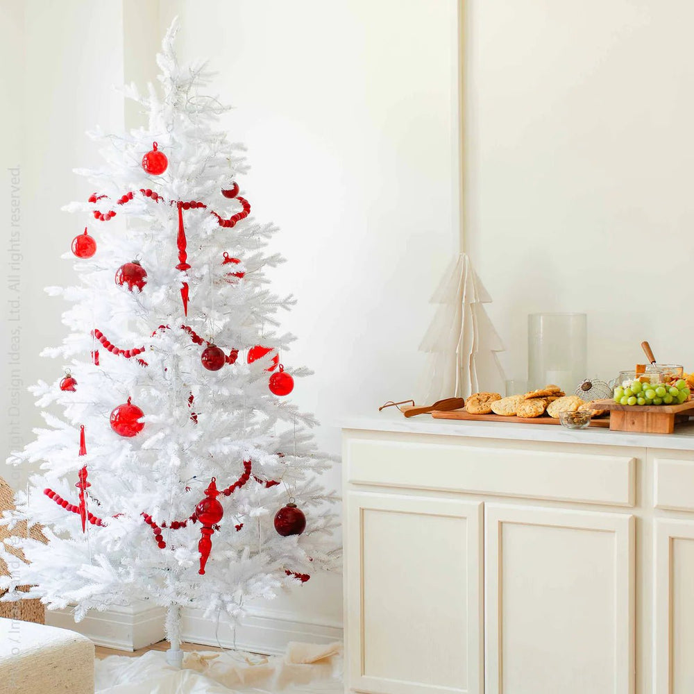 Moroah™ Mouth Blown Red Glass Ornaments on white tree next to holiday spread.