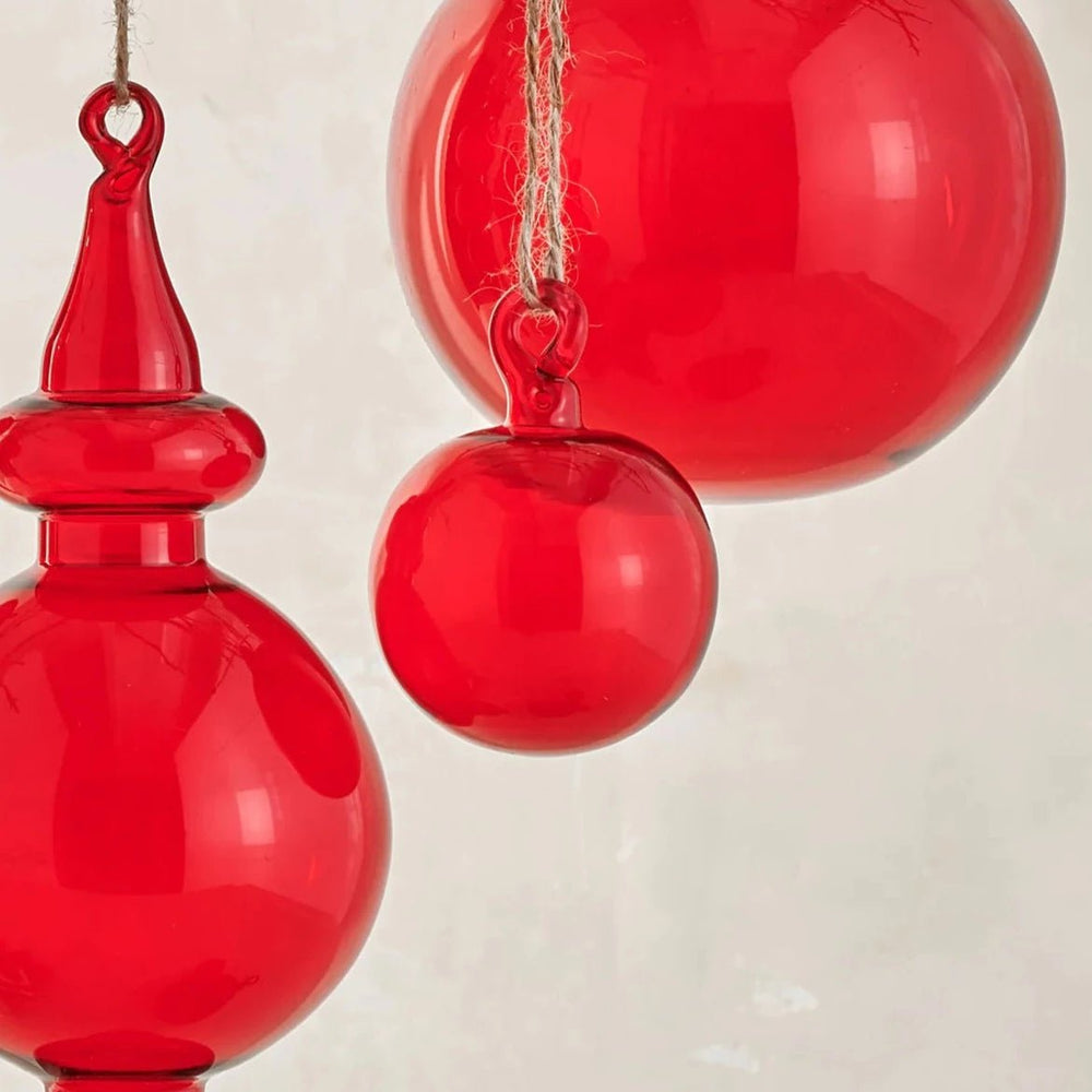 
                      
                        Moroah™ Mouth Blown 2 Inch Red Glass Ornament next to other red glass ornaments against neutral background
                      
                    