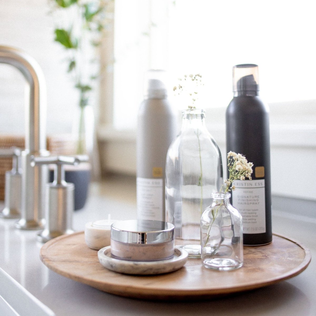 Takara™ Teak Root Centerpiece Plate holding various decorative items placed next to sink faucet.